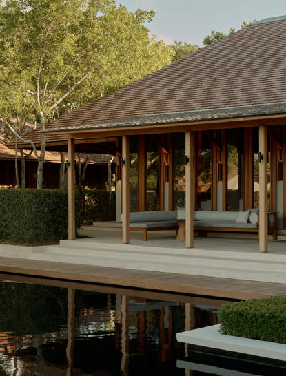 Exterior view of the wellness spa at Amanyara resort in Turks and Caicos, featuring wooden architecture and peaceful water reflection.