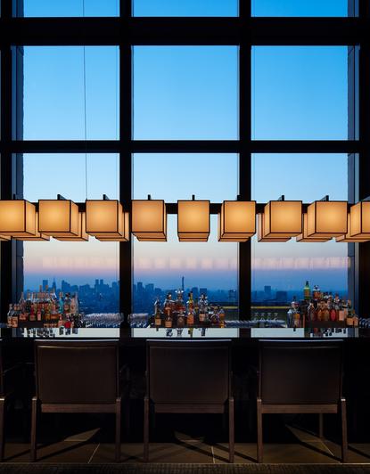 アマン東京のラウンジバーから夜景を眺める窓とオレンジ色のクッション付きシーティング。