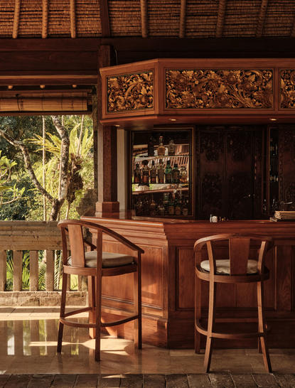 Amandari resort bar in Ubud with wooden furnishings, carved panels and views to tropical gardens.