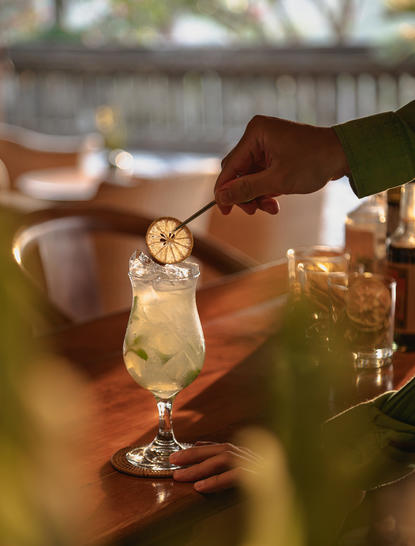 Amandari resort bar in Ubud, Bali: bartender pouring cocktail into glass with ice and garnish.