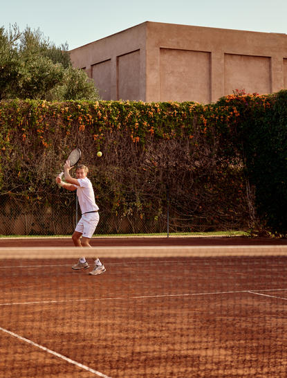 Tenista in azione sul campo in terra battuta di Amanjena, Marrakech.