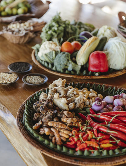 Ingredients for harvest table at Amankila resort arranged on wooden platters, including fresh vegetables and herbs.