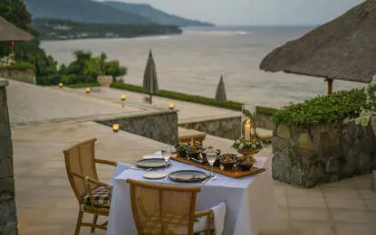 Rijsttafel dinner setup by the pool at Amankila resort, Bali, overlooking terraced landscapes.