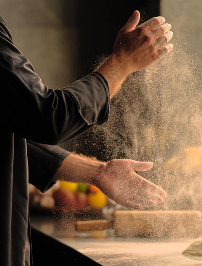 Chef's hands dusting flour during Italian cooking class at Amanpuri resort, Thailand.