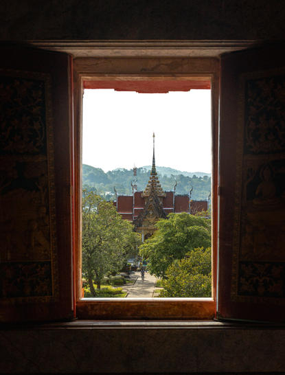 Veduta dal resort Amanpuri verso un tempio tailandese circondat da vegetazione collinare.