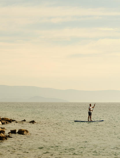Person stand-up paddleboarding on calm turquoise waters at Amanruya, Turkey.
