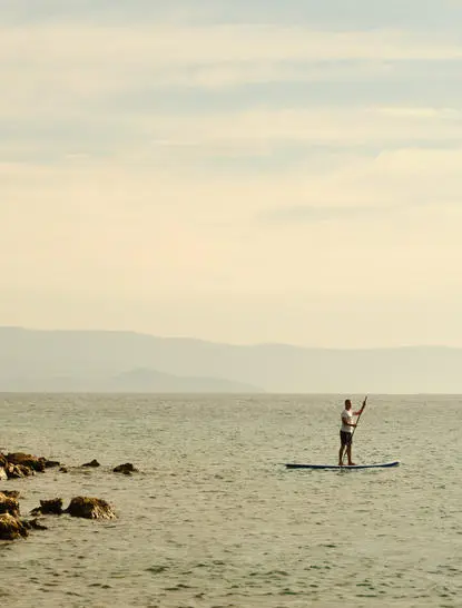 Person stand-up paddleboarding on calm turquoise waters at Amanruya, Turkey.