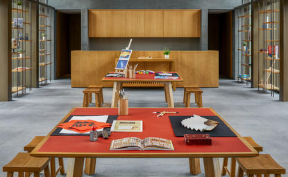 养云安缦文化发现中心内，木质展示柜前摆放着传统工艺品和书籍的展览台。