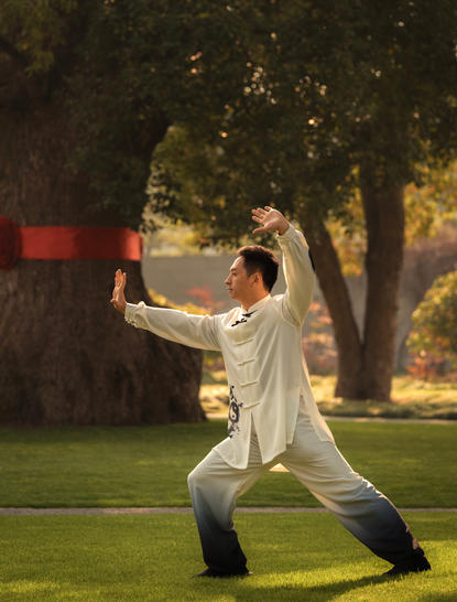 Woman in white shirt practising tai chi on a lawn at Amanyangyun, China, at dusk.