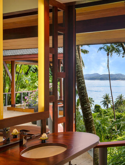 Pavilion with ocean views, palm trees, and wooden furnishings at Amanpuri resort.