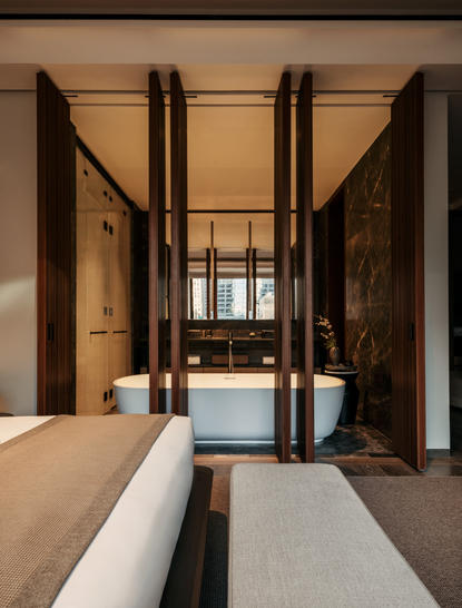 Ingresso della camera con pareti in legno scuro e letto bianco presso Aman New York.