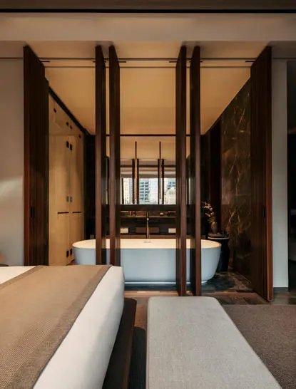 Principal bedroom with floor-to-ceiling dark wooden doors and bed at Aman New York.