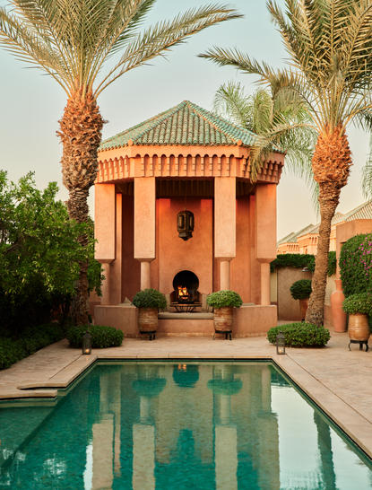 Al-Hamra room at Amanjena, Morocco, with terracotta building, plunge pool and palm trees.