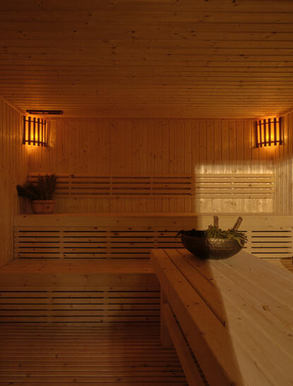 Intérieur chaleureux du sauna Banya à Amanpuri, avec bancs en bois et lumière ambrée, Thaïlande.