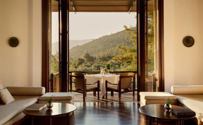 Private dining room at Amanruya with views towards Turkish mountains and countryside beyond open doors.