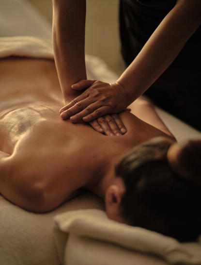 Therapist's hands performing a back massage on a guest at Amansara spa, Cambodia.