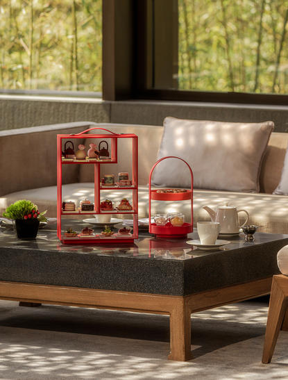 下午茶服务陈列在养云安缦度假村的低矮木质茶几上，配以红色分层点心架和精致的茶具。