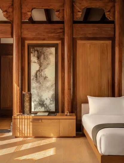 Antique wooden pavilion bedroom with carved panels and artwork at Amanyangyun, China.