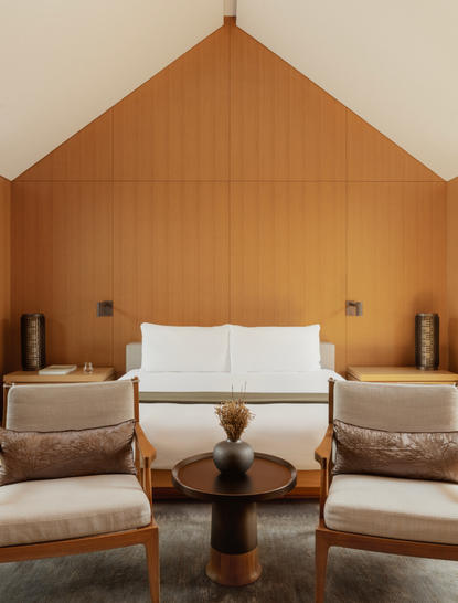 Ming Pavilion bedroom at Amanyangyun with symmetrical seating arrangement beneath pitched wooden ceiling.