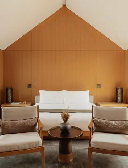 Ming Pavilion bedroom at Amanyangyun with symmetrical seating arrangement beneath pitched wooden ceiling.