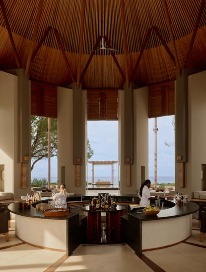 Bar au resort Amanyara avec baies vitrées offrant une vue sur l'océan et plafond voûté en bois.