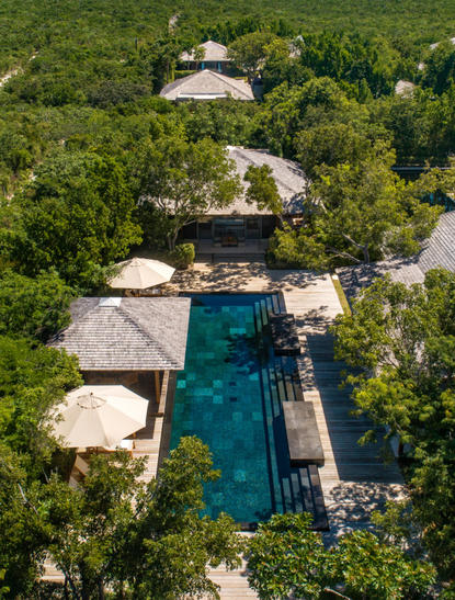 Aerial view of a five-bedroom beach sala villa at Amanyara surrounded by lush tropical vegetation and a turquoise lagoon.