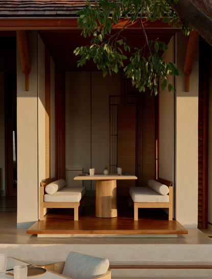 Eingang zum Hauptrestaurant von Amanyara mit hölzernem Tisch und Stühlen unter Grünpflanzen.