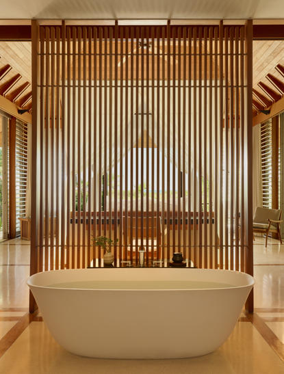 Ocean Cove Pavilion bathtub at Amanyara, with wooden slat backdrop and warm lighting.