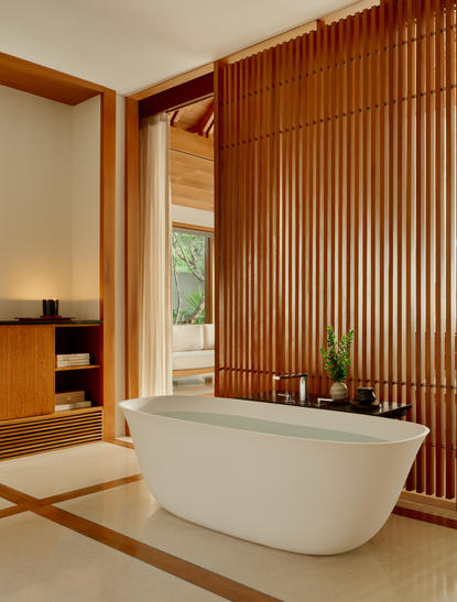 Ocean Pavilion bathroom with wooden accent wall and freestanding soakingbathtub at Amanyara, Turks and Caicos.