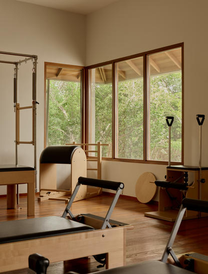 Spa treatment room at Amanyara resort with floor-to-ceiling windows overlooking tropical gardens and wooden massage furniture.