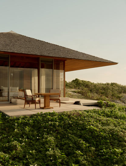 The Artist's Villa at Amanyara with modernist architecture, expansive glazing and wooden overhang, surrounded by lush vegetation.