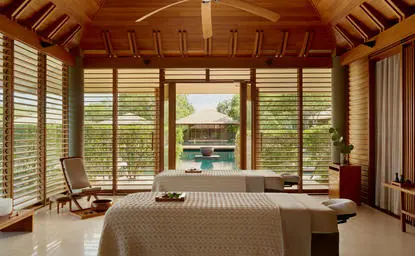 Wellness room with wooden ceiling and shuttered windows overlooking tropical gardens at Amanyara resort, Turks and Caicos.