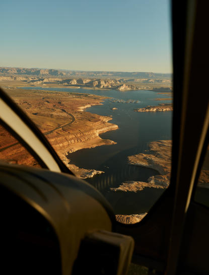 Aerial view from a private aircraft window showing desert landscape meeting blue water near Amangiri, Utah.