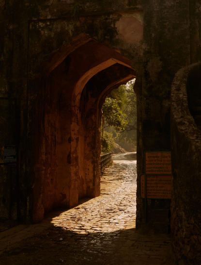 Sunlit pathway through a weathered stone archway at Aman-i-Khas.