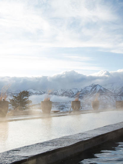 Amangani's outdoor soaking pool overlooking snow-covered mountains and forested valleys below.