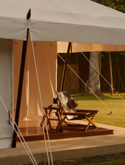 Exterior view of a lounge tent at Aman-i-Khas, India, featuring wooden furnishings and warm lighting.