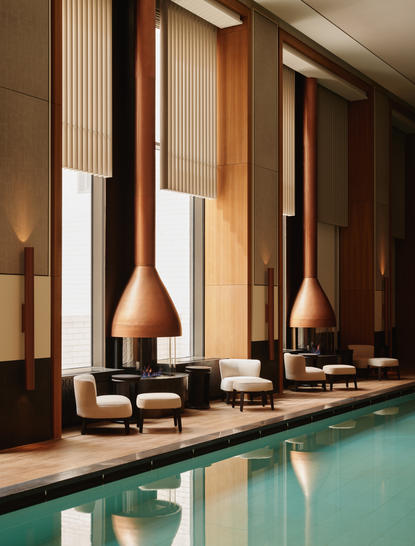 Piscina de bem-estar do Aman New York com água azul-turquesa e lareiras modernas ao fundo.