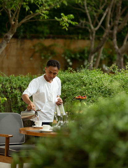 Private butler preparing refreshments amongst tropical gardens at Aman Villas at Nusa Dua.