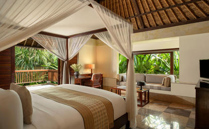 Principal bedroom with four-poster bed, wooden beams, and garden views at Aman Villas at Nusa Dua.