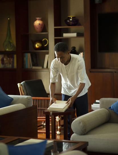 Woman reading in the library at Aman Villas at Nusa Dua, Indonesia, surrounded by shelves and warm lighting.