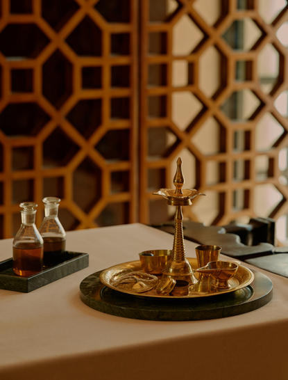 Dining table at Amanbagh with geometric patterned screens and lit candles reflected in polished surfaces.