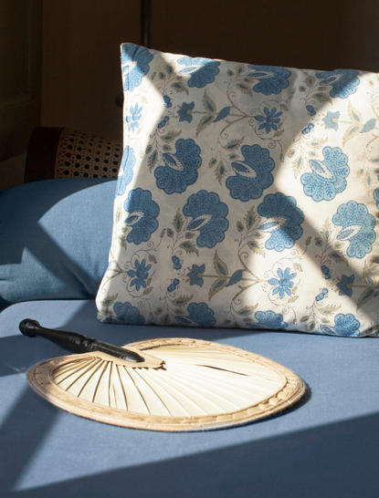Decorative pillow with blue floral pattern and round woven plate detail at Amangalla, Sri Lanka.
