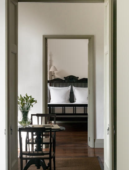 Corridor at Amangalla with view through doorway to mirrored room and wooden furniture.