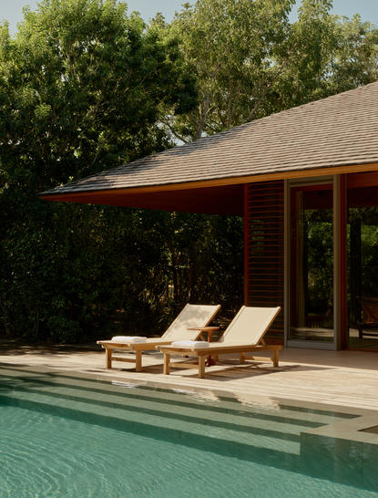 アマンヤラのリゾートにあるプール・パビリオン。木製のラウンジチェアが並び、静寂に満ちた空間。