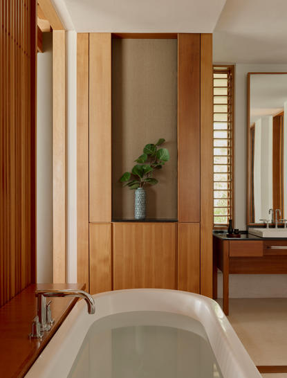 アマンヤラのヴィラの浴室。木製パネルと大きな窓のある現代的な空間に、自然光が注ぐ浴槽。