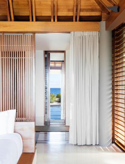 安缦涯澜度假村海湾馆阁的细部景观，展示木质天花板、百叶窗和通往露台的玻璃门。
