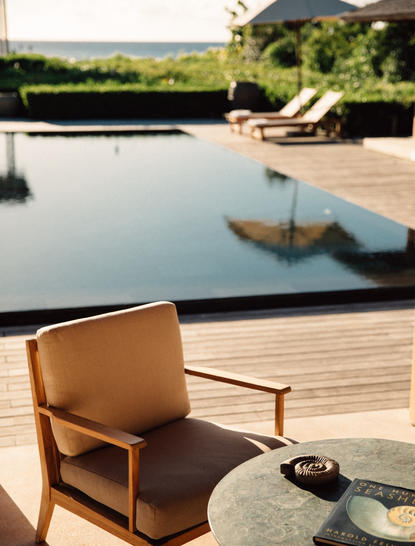 安缦涯澜度假村的四卧海滨别墅，木质平台上放置着米色扶手椅，俯瞰无边际泳池和海景。