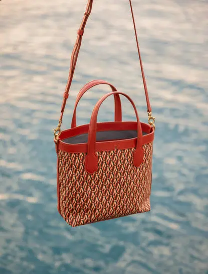 Amanpuri Rust Mini Tote bag displayed against blue water at the resort.