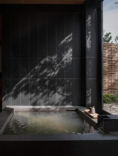 Uchiyu onsen bathing pool at Amanemu resort, with steaming water and natural light filtering through timber screens.