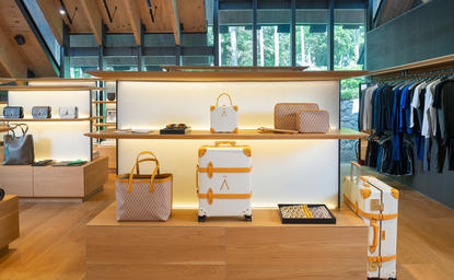 Aman Essentials Boutique at Amanpuri resort, displaying clothing and wellness products on wooden shelving and display surfaces.
